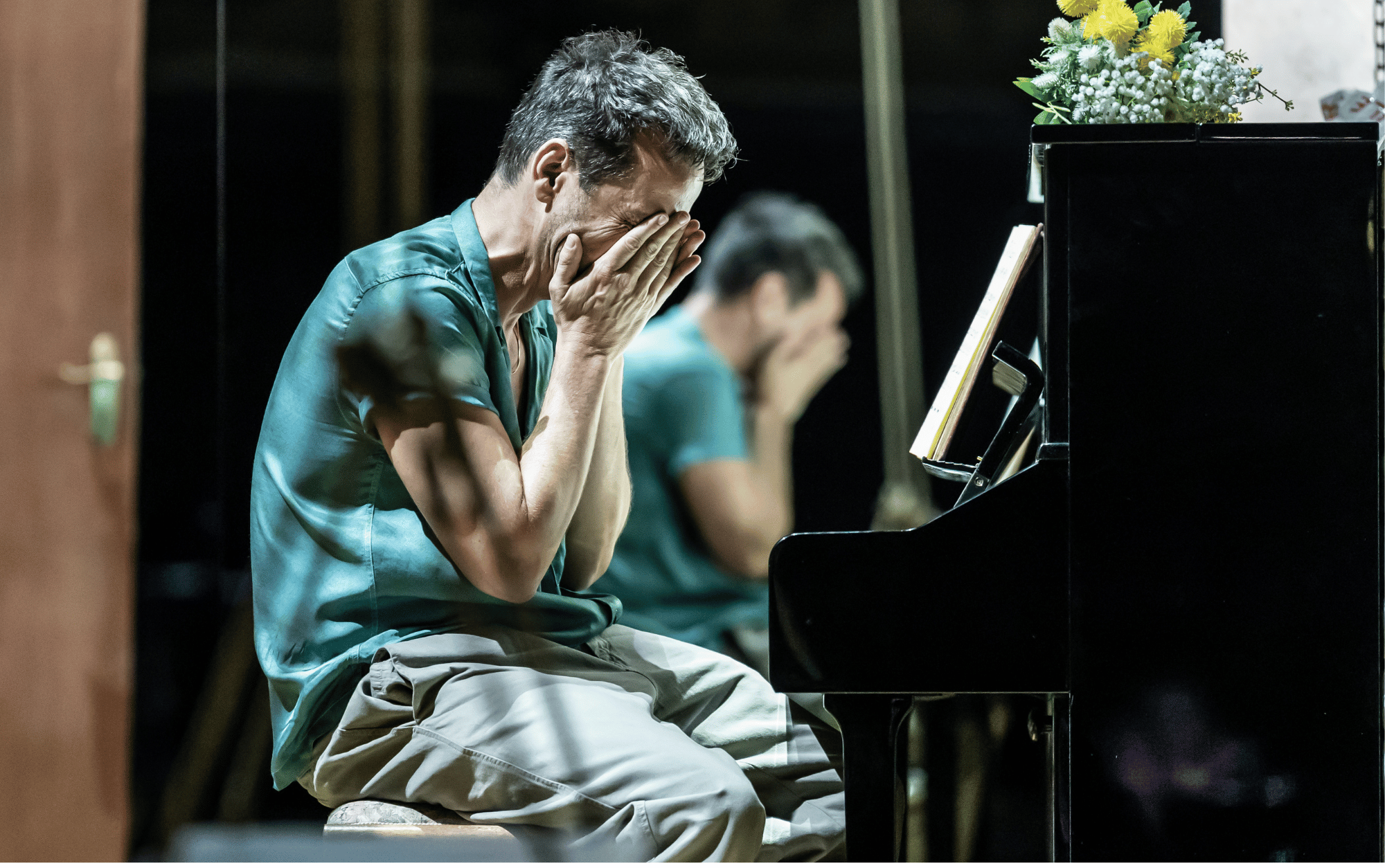 Actor Andrew Scott sitting on a stool, hands in hands, as if crying.  His reflection is seen in a mirror