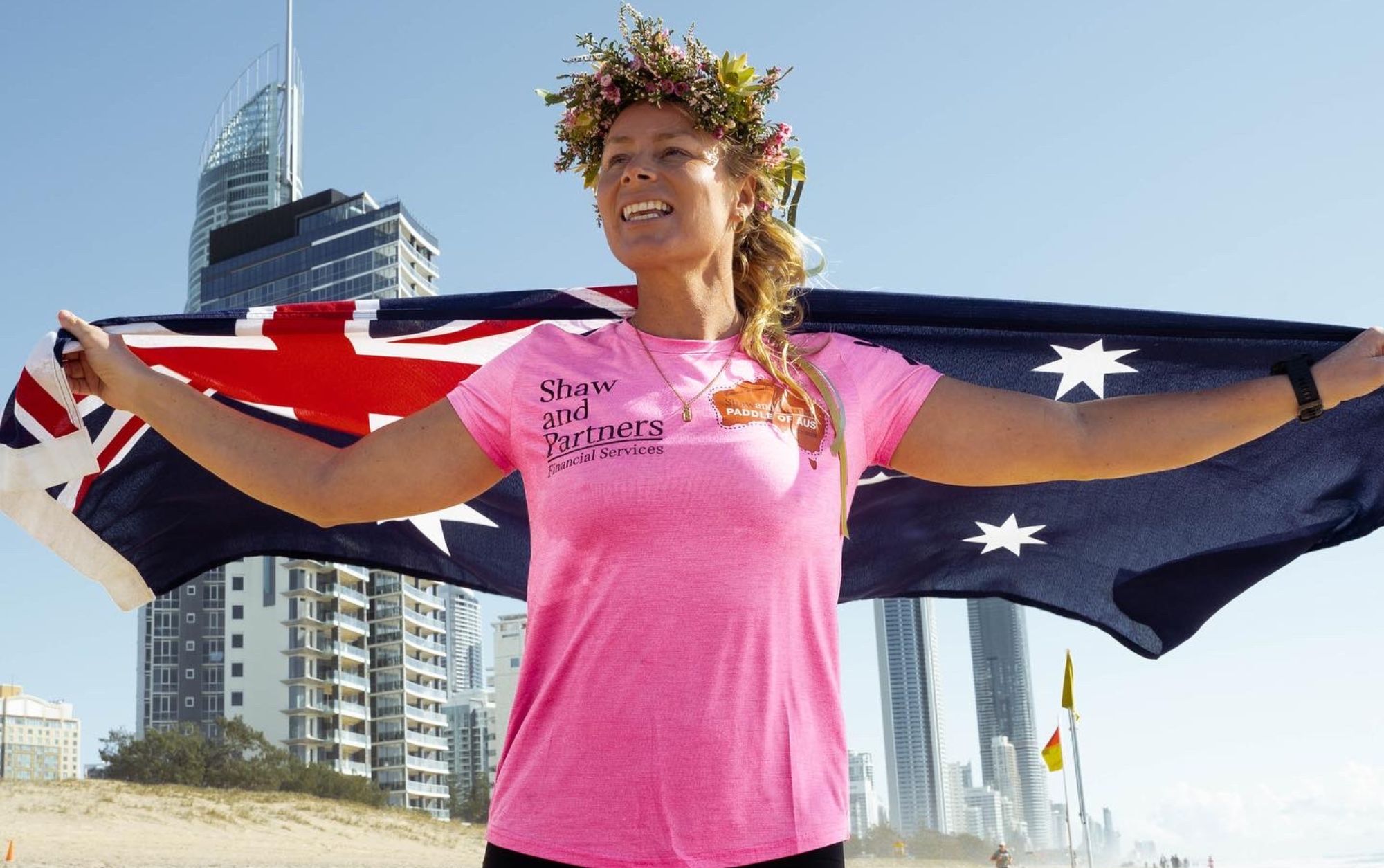 Bonnie hancock holding australian flag over her shoulder in a pink rashguard