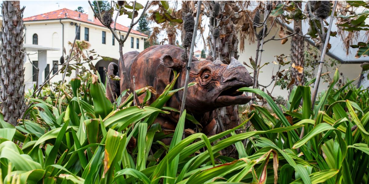 A large giant puppet rhino hiding amongst the trees at the Bondi Pavilion 