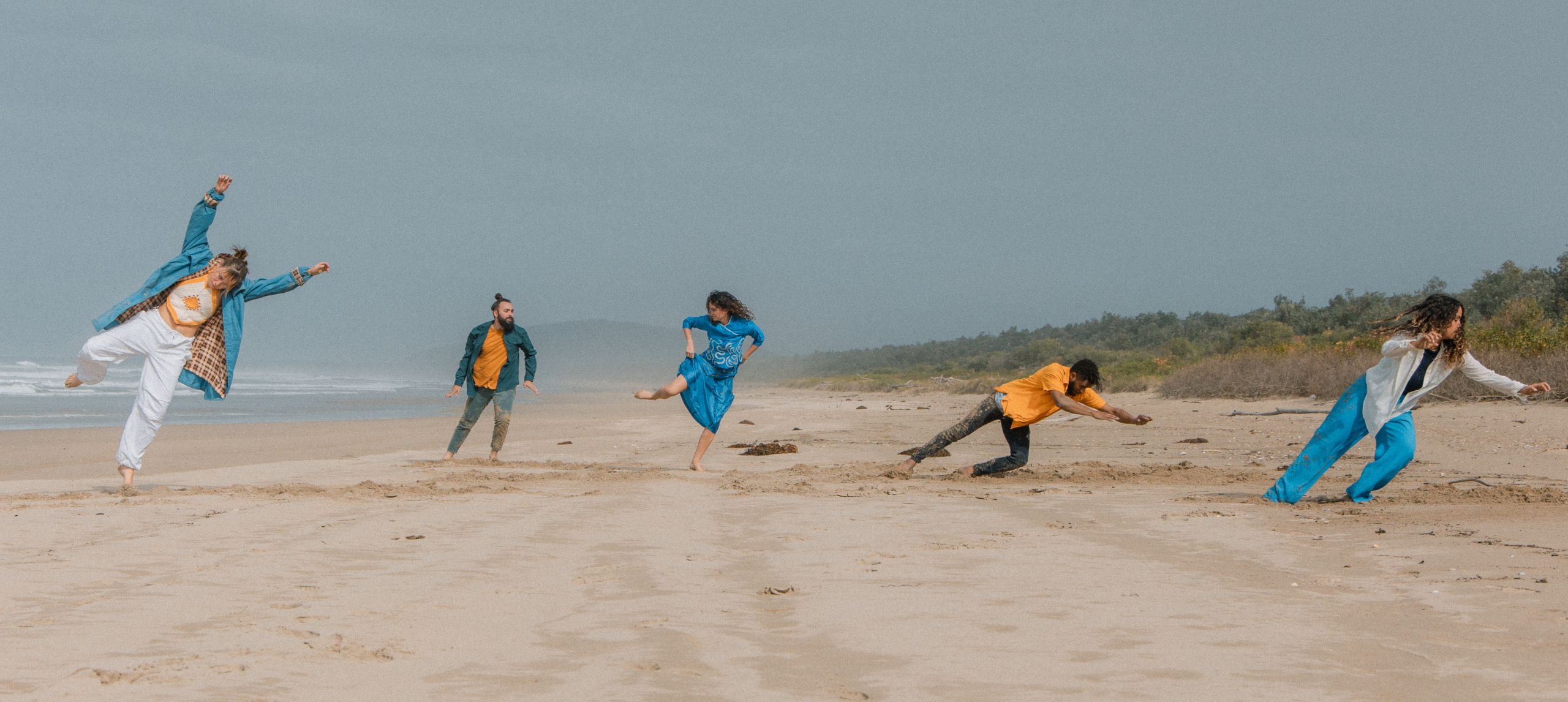 Dancers in a line at the beach in various dance moves