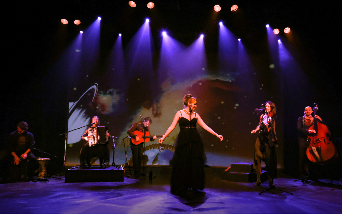 Six musicians on stage, with purple coloured down lights and stage