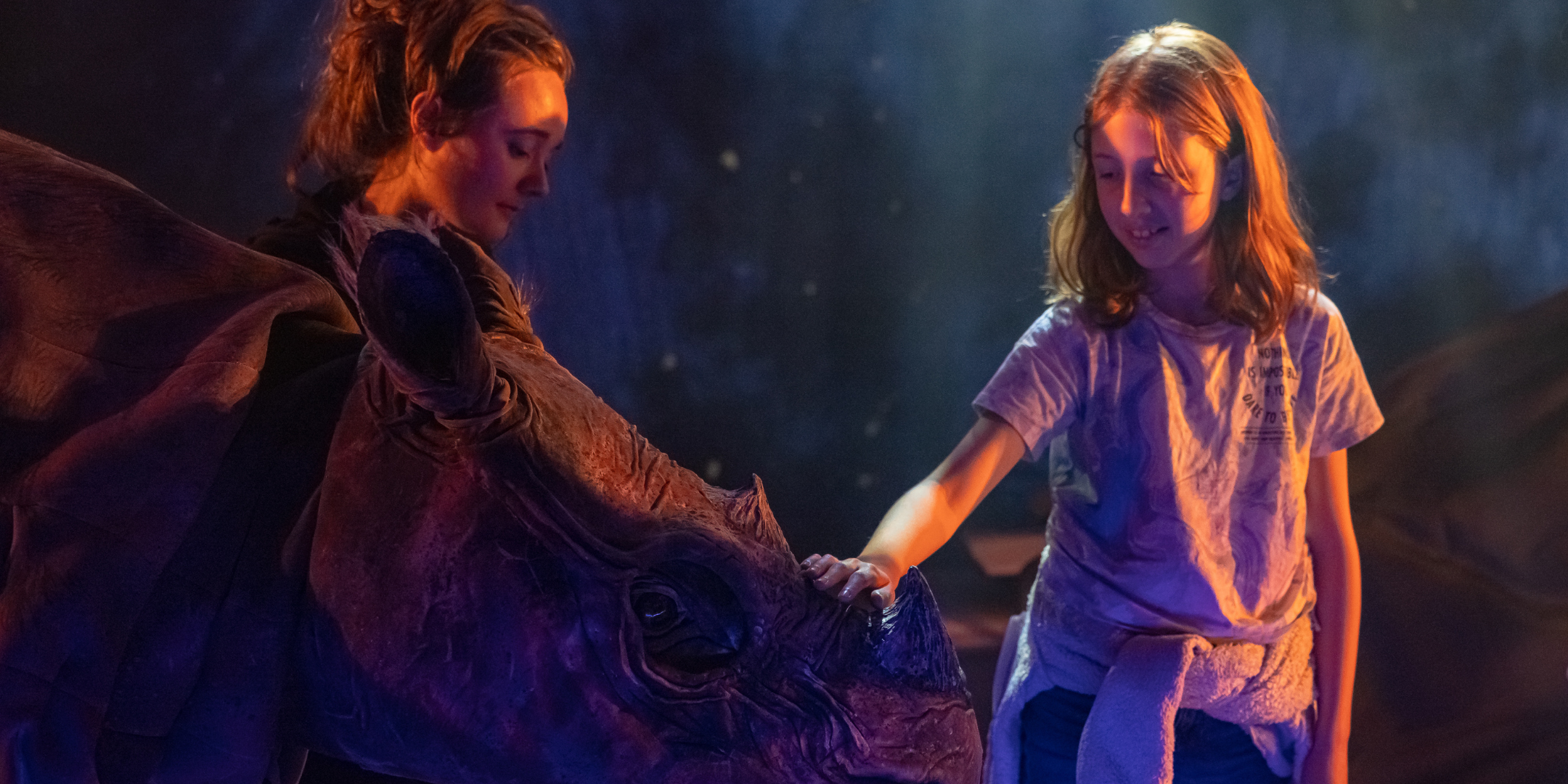 A young girl holding the hand of a large-scale puppet with the workshop tutor