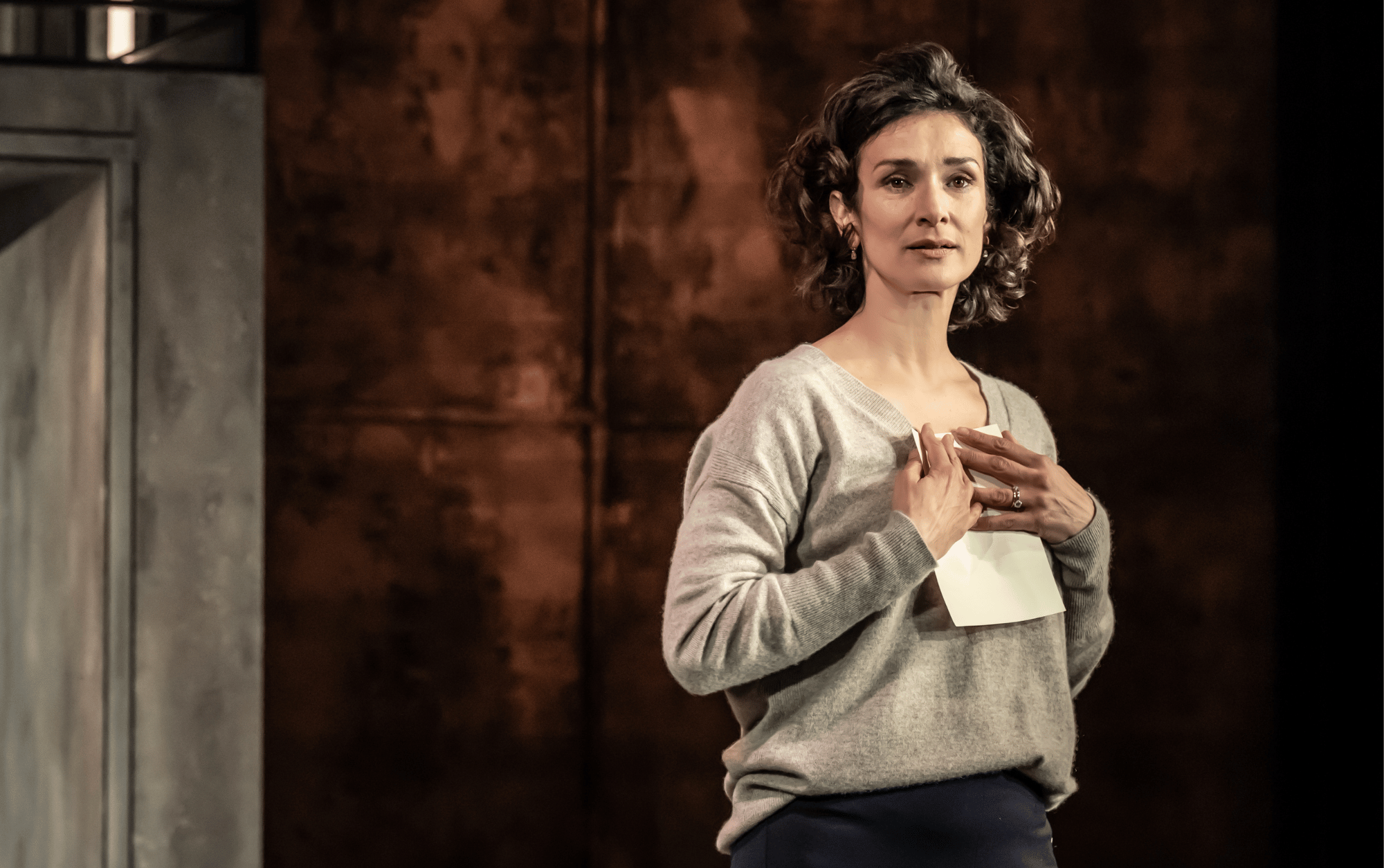 Indira Varma as Lady Macbeth, standing on stage looking at camera