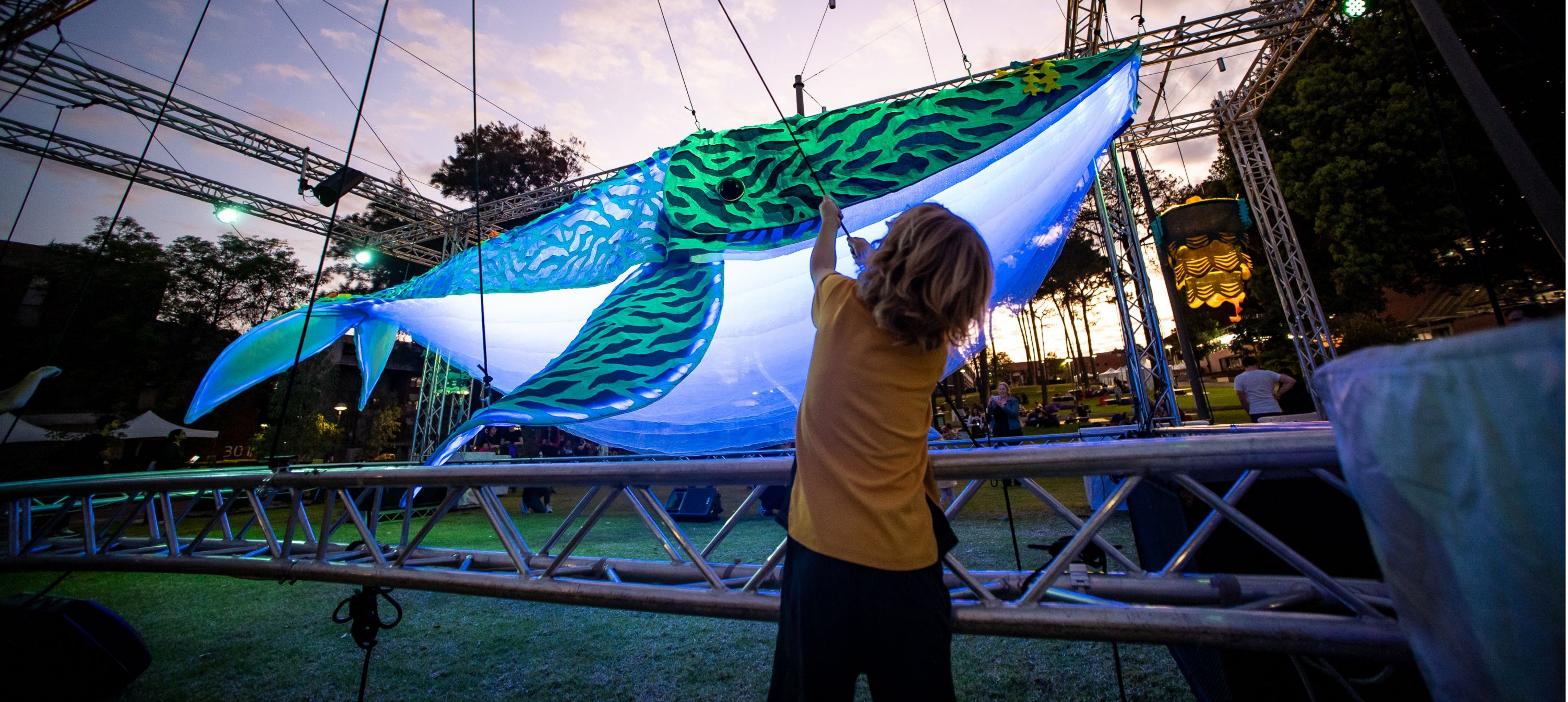 Large suspended whale with young person pulling at a string to move it