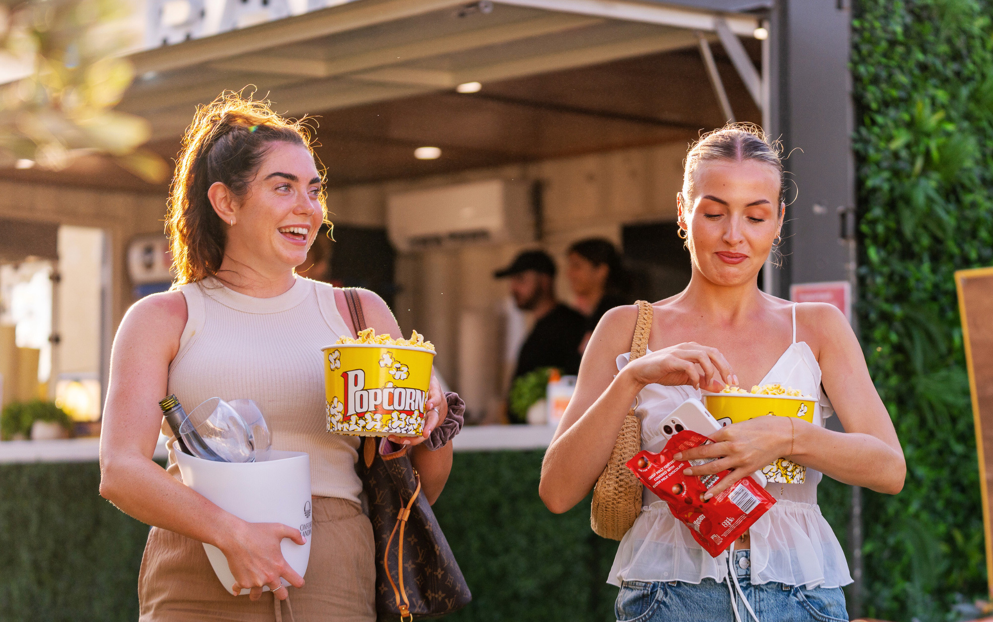 Two young women walking with popcorn bucket and snacks