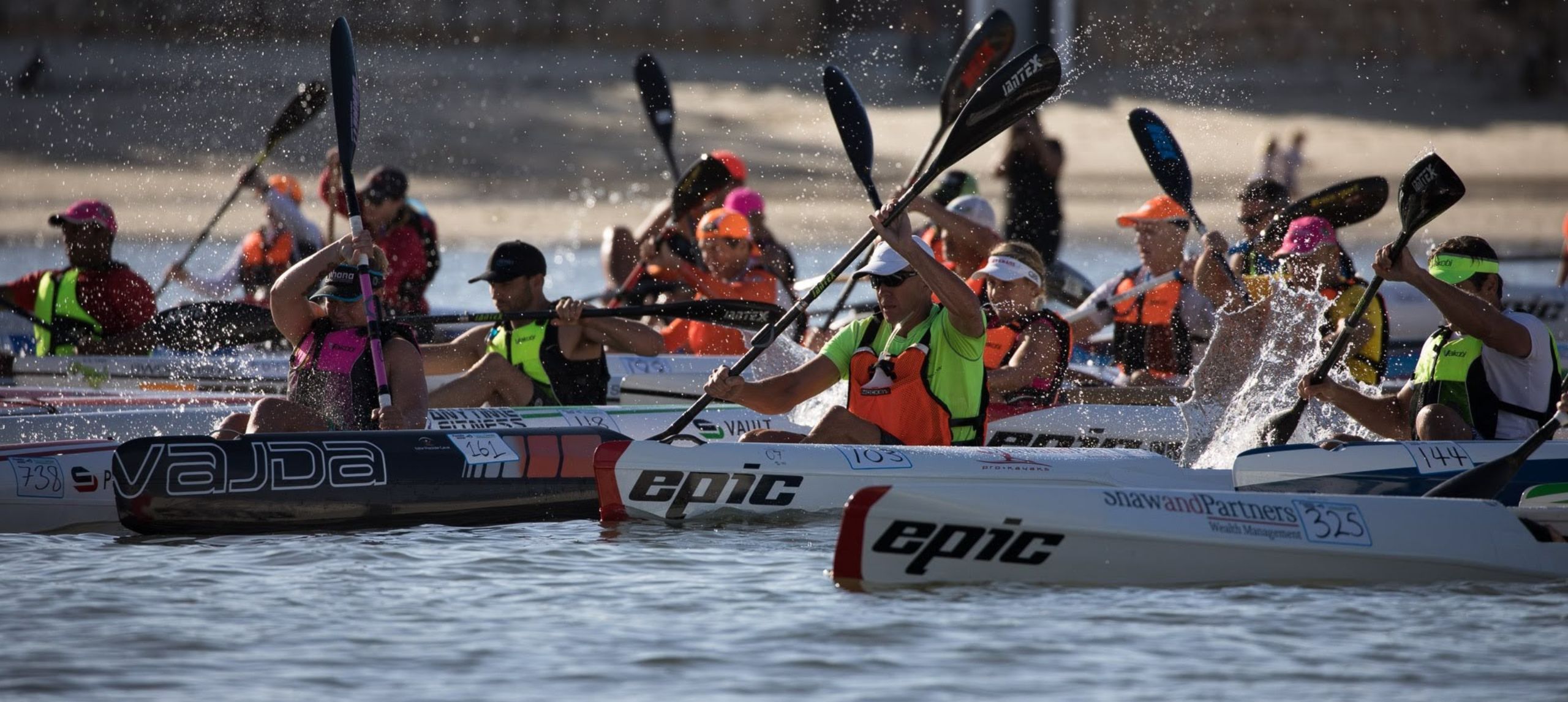 A bunch of ocean paddlers in a race wearing neon jerseys