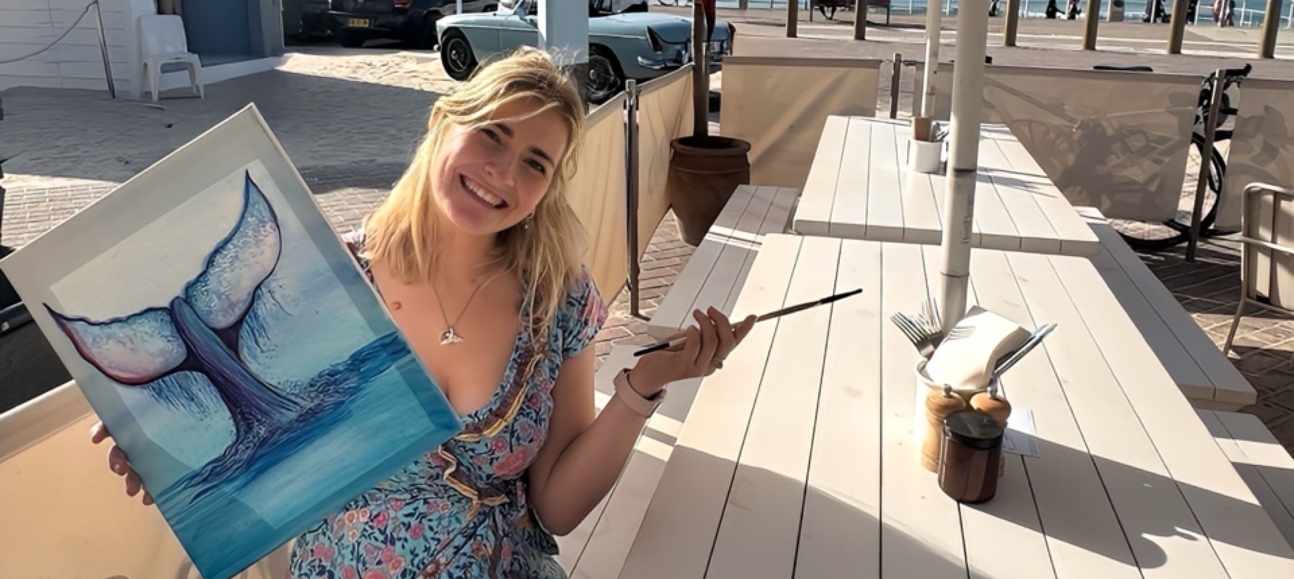 Painting teacher sitting at picnic table with painted whale on canva