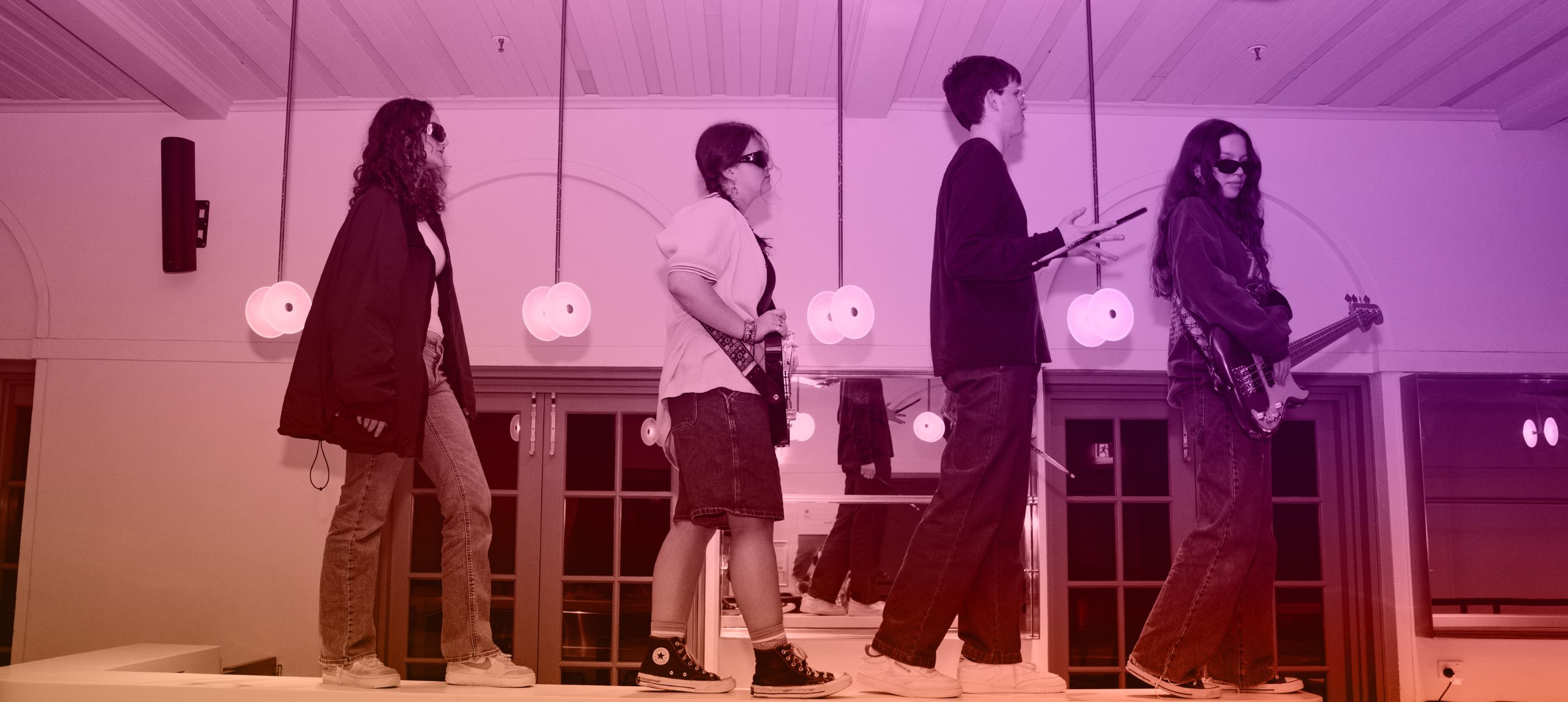 4 music students standing on top of bar facing towards the right with their instruments