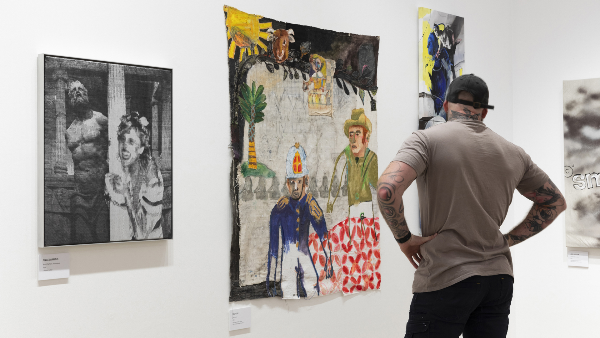 A photograph of a man in the Bondi Pavilion Gallery looking at a wall of artworks. 