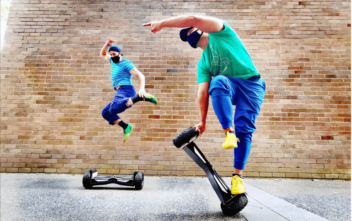 Two dancers on hover boards in a room with brick walls