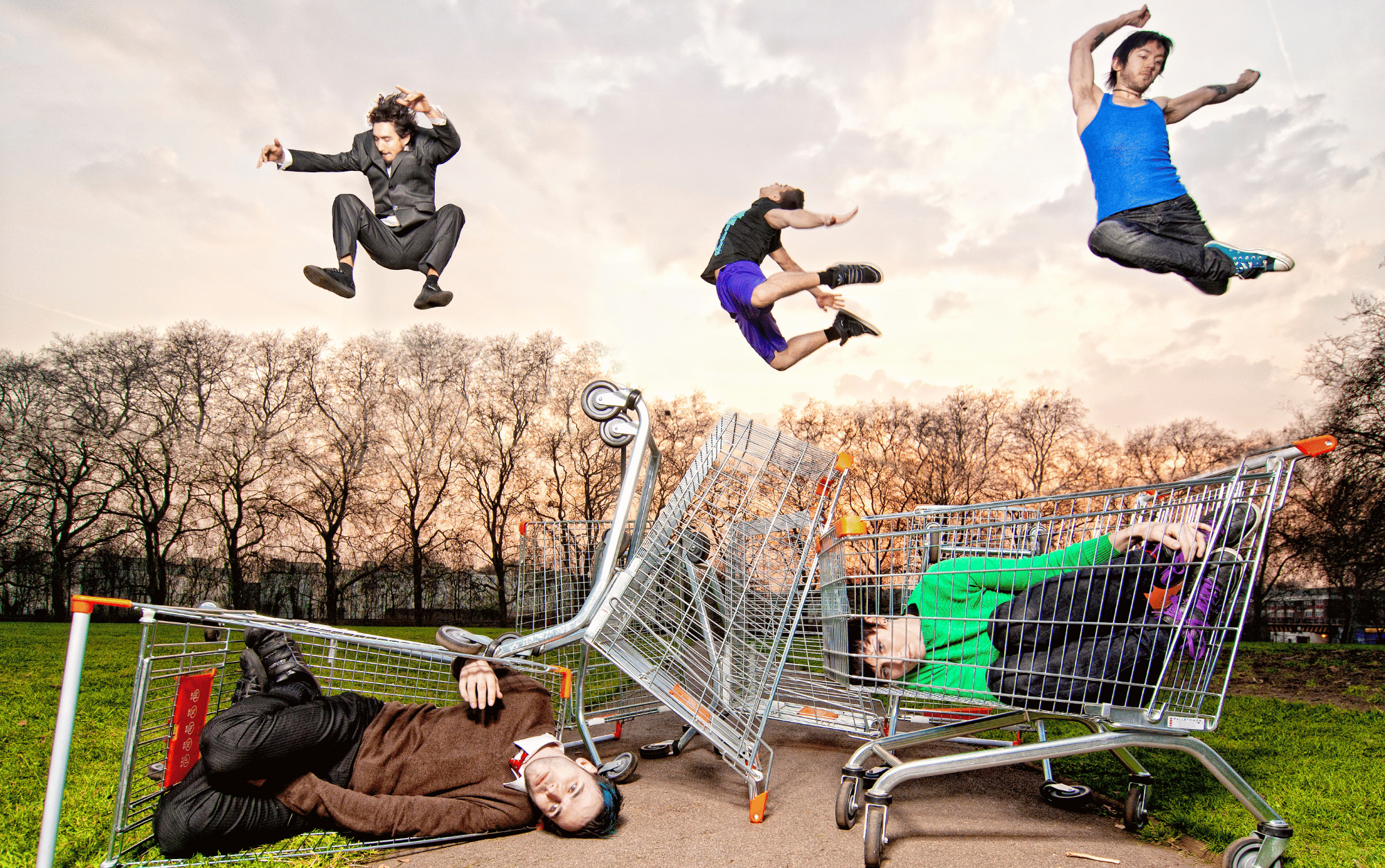 Three dancers leaping above shopping trolleys