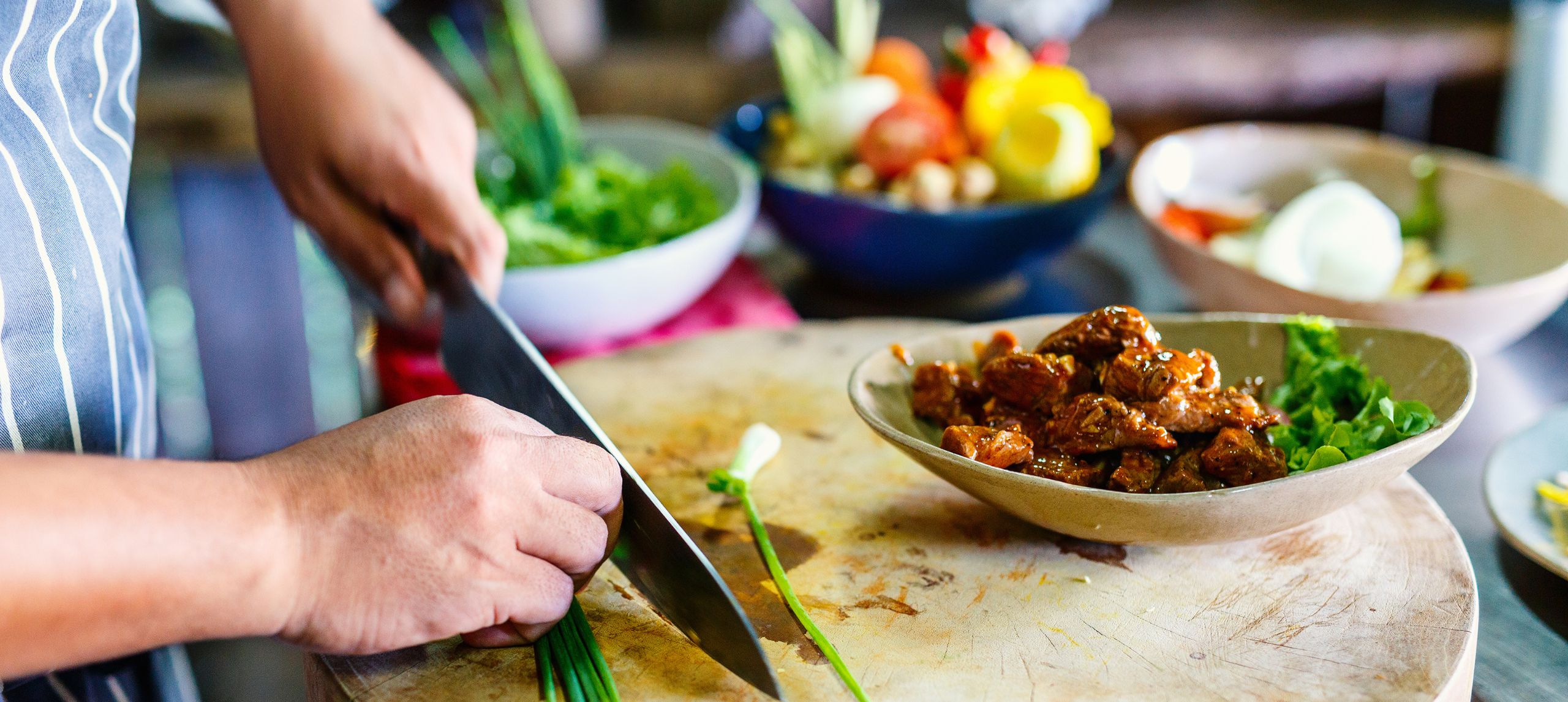 hands chopping a vegtable with blurred vegetables in the background