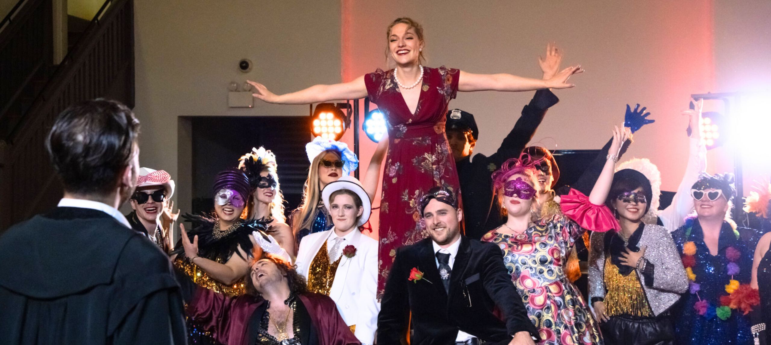 Group of young opera singers on stage in formal wear with opera masks