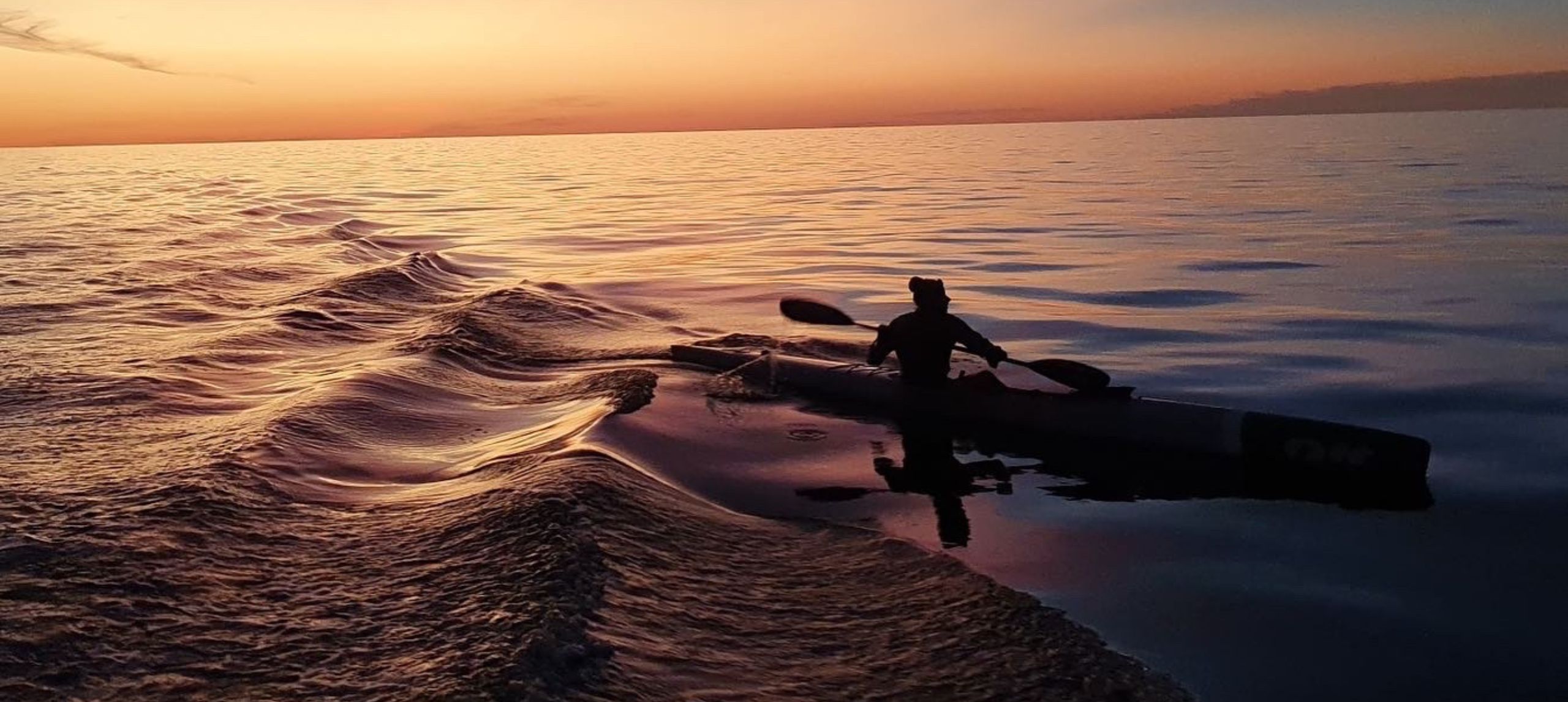 Women on paddle boat at sunset on a calm sea